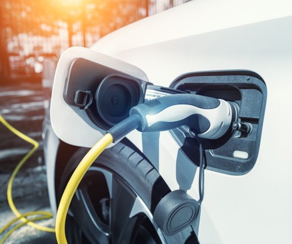 Close-up modern electric plug-in hybrid car parked near fast charger charging station