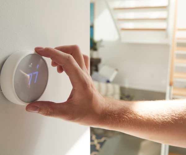 Close Up Of Male Hand Adjusting Digital Central Heating Thermostat In Home