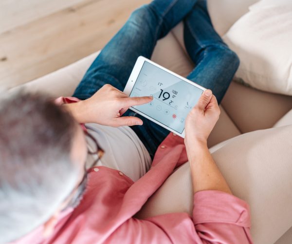 Man using smart thermostat, adjusting, lowering heating temperature at home. Concept of sustainable