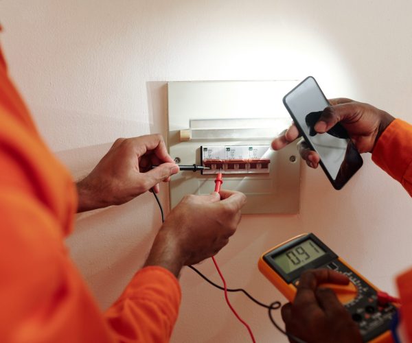 Hands of technicians using multimeter when testing electric current in Watt hour meter